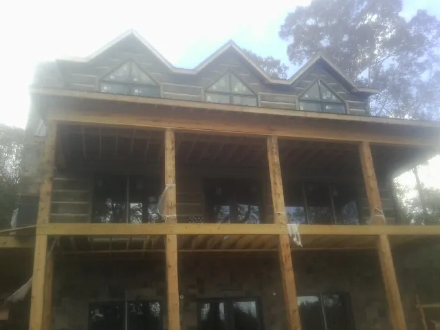 Dormers and porch framing on a large log home under construction — Roof Coating work by our crew in Jakin