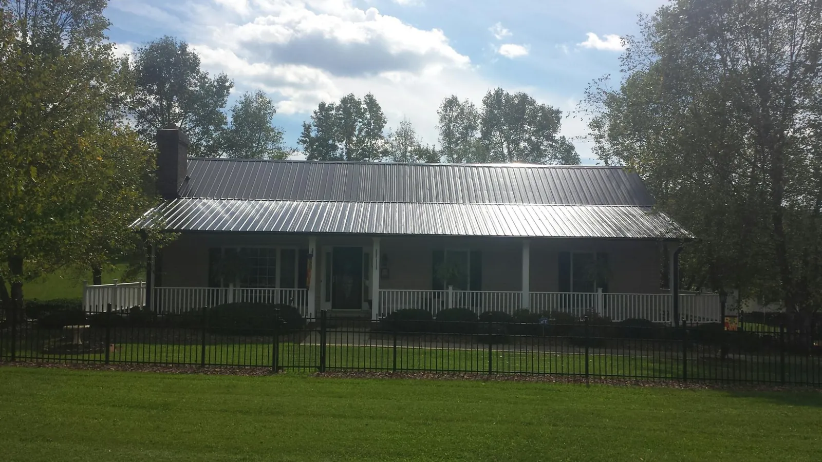 Gray metal roof on a brick ranch with a full width front porch — Gutter Guard Installation work by our crew in Jakin