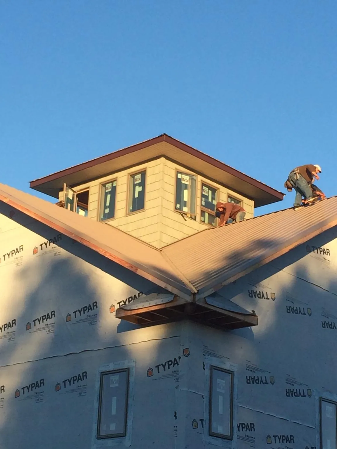 Roofers working around a rooftop cupola on a new metal roof at sunset — Roof Waterproofing in Jakin by Roofing Brothers